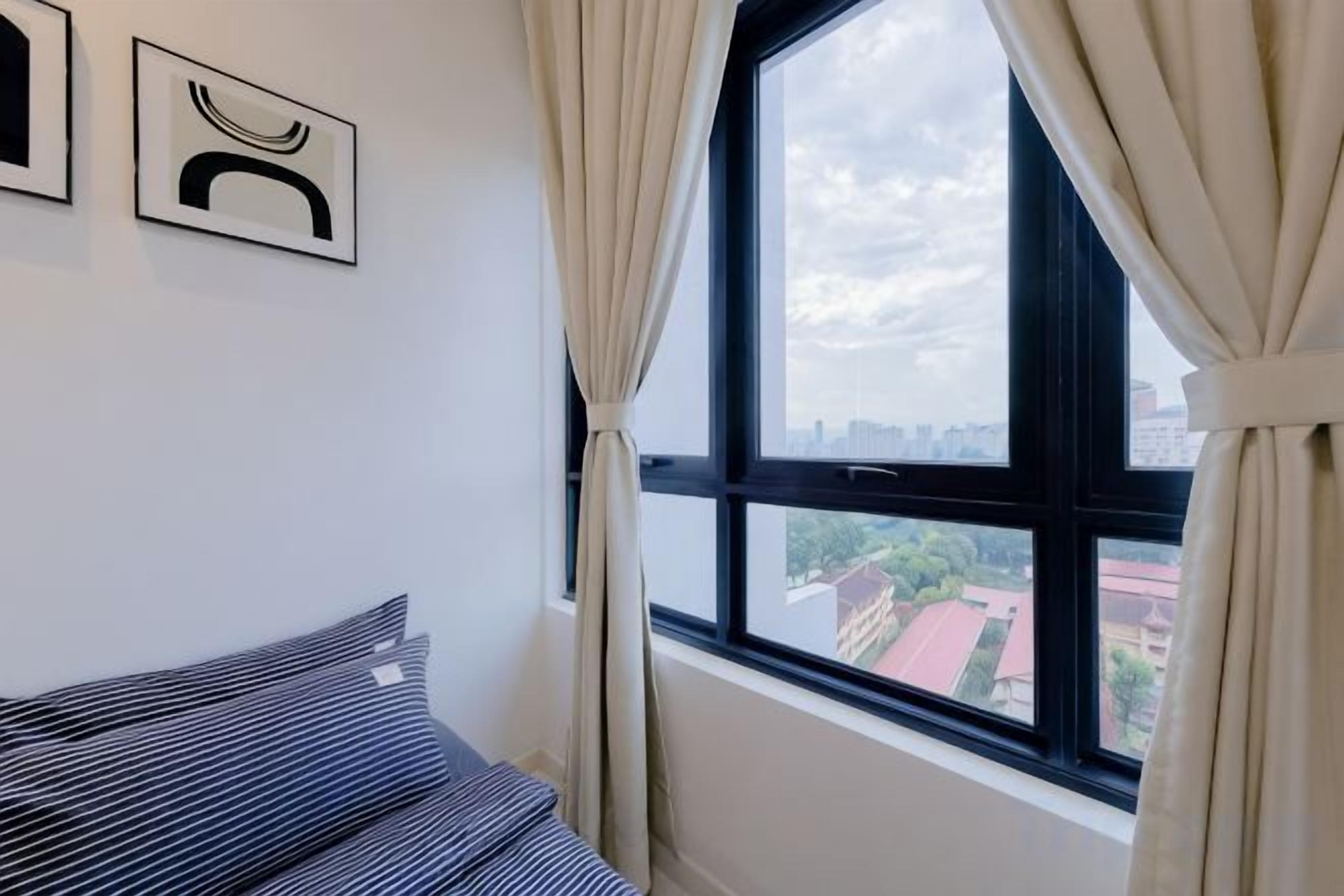 A room with a bed, a window with curtains, and two framed pictures on the wall.