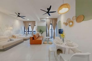 A modern living room with a sofa, a dining table with chairs, ceiling fans, and decorative wall art. - THE PANO BY FEEL HOME (Kuala Lumpur)
