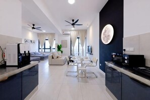 Eine moderne Küche mit Essbereich, ein Wohnzimmer mit einer Couch und einem Deckenventilator.
