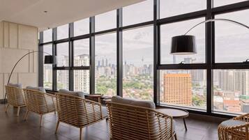 A modern interior with large windows, wicker furniture, and a city view.