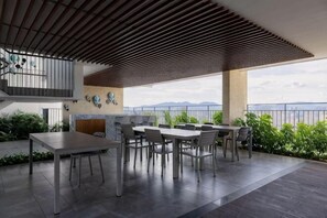 Une terrasse extérieure dotée d’un plafond en bois, d’une table à manger avec des chaises et offrant une vue sur les montagnes.
