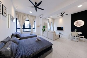 Ein modernes Hotelzimmer mit zwei Betten, einem Deckenventilator, einem Fernseher, einem Schreibtisch und einem großen Fenster.