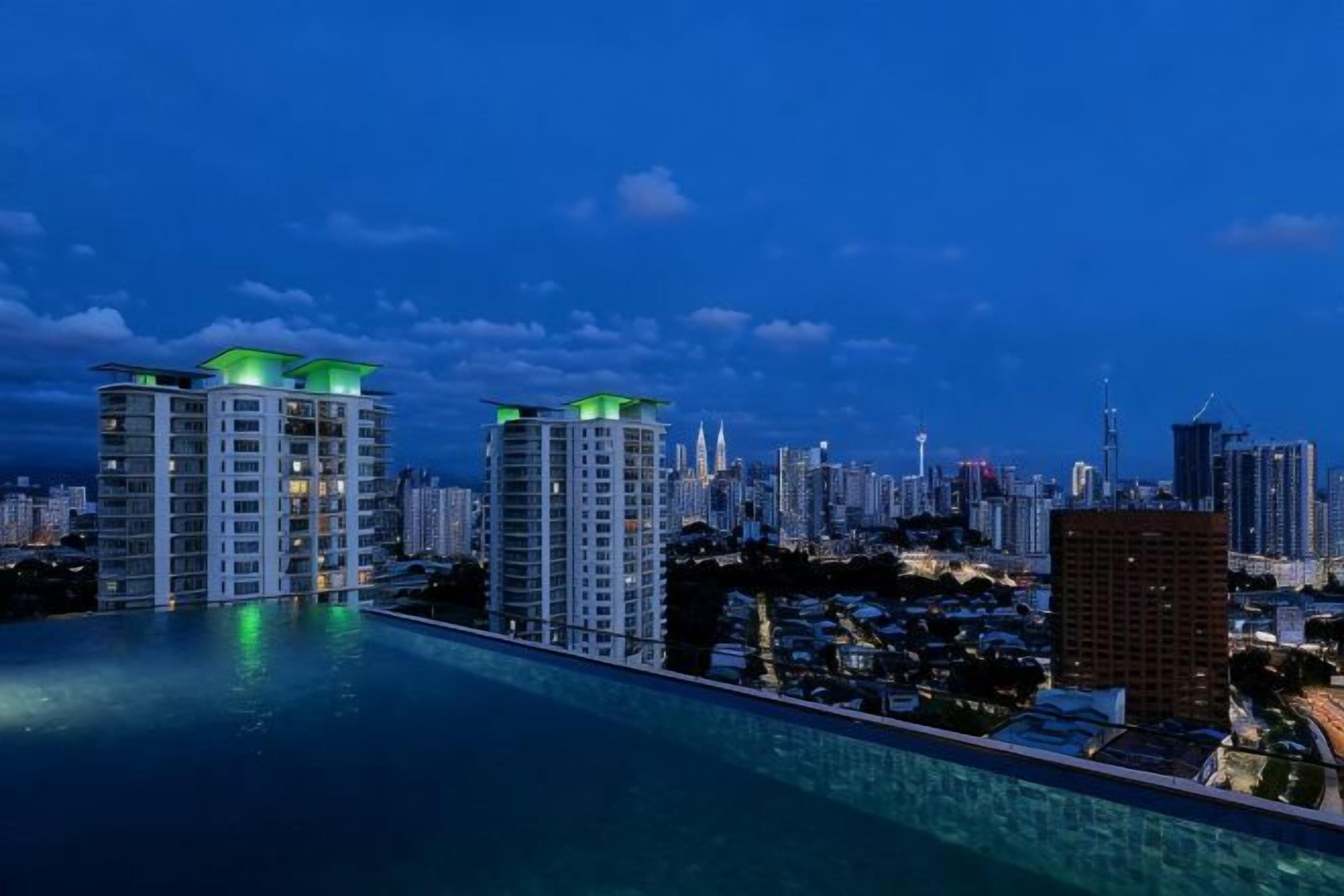 A cityscape at dusk with high-rise buildings and a pool.