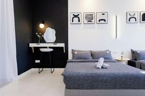 Une chambre à coucher moderne, dotée d’un lit, d’un bureau et d’une chaise, et caractérisée par un design minimaliste et une œuvre d’art accrochée au mur.