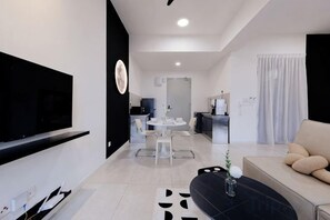 Una sala de estar moderna con un televisor de pantalla plana, un sofá y un comedor con mesa y sillas.