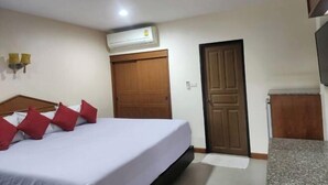 A hotel room with a bed, a wooden door, an air conditioning unit, and a wall-mounted light fixture. - Amorn inn resort (Chiang Rai)