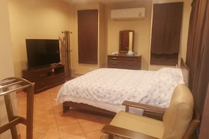 A hotel room with a bed, a television, a desk, and a chair. - Ben's house (Chon Buri)