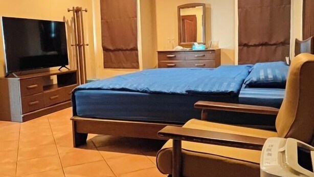 Ένα δωμάτιο ξενοδοχείου με ένα κρεβάτι, μια τηλεόραση, ένα κομοδίνο, μια καρέκλα και έναν καθρέφτη.