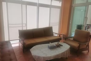 A living area with a sofa, armchair, and round table. - Ben's house (Chon Buri)
