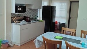 Μια μικρή, λειτουργική κουζίνα με ψυγείο, φούρνο μικροκυμάτων και νεροχύτη. Διαθέτει επίσης ένα τραπέζι φαγητού με καρέκλες.