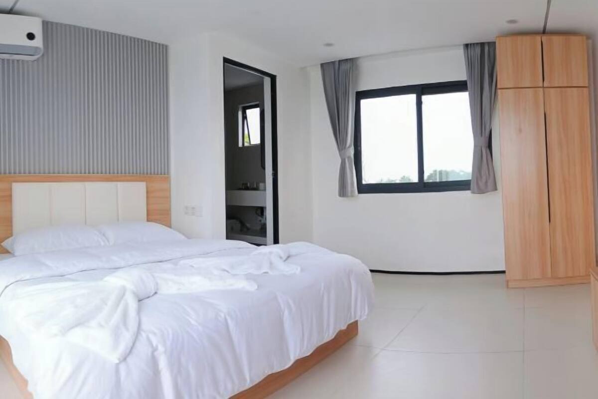 A bedroom with a bed, a wardrobe, and a window with curtains.