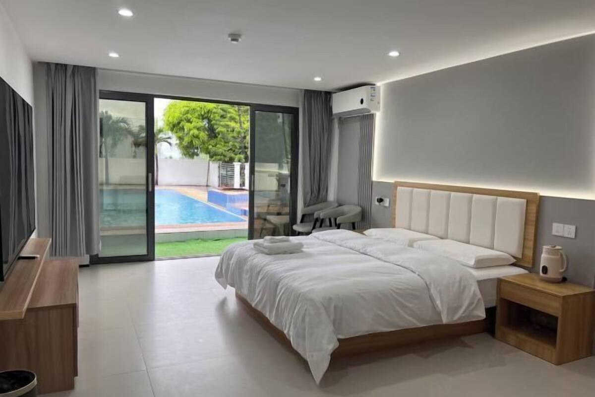 A modern bedroom with a large bed, a wooden nightstand, a desk, and a chair.