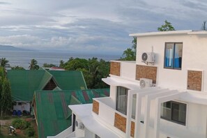 A multi-story building with a flat roof, air conditioning units, and a view of the sea.