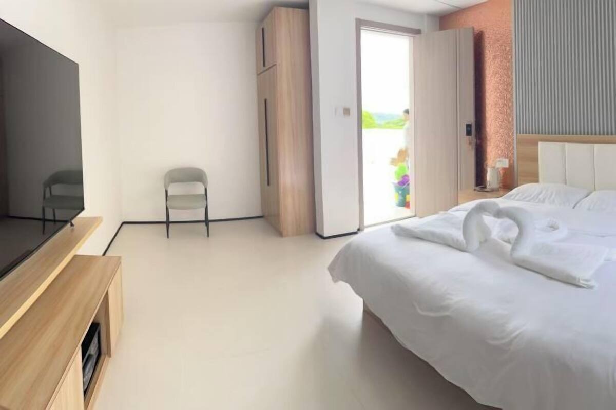 A hotel room with a bed, a TV, a wardrobe, and a chair.