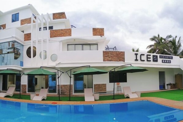 A modern hotel with a pool, outdoor seating, and a sign reading 'ICE HOTEL.'