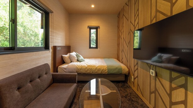 A compact room with a sofa, a bed, a TV, and a window. - MAX CUBE Inami Seafront (Inami)
