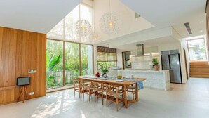 A spacious kitchen with a large island, wooden dining table, and chairs. - Stunning Luxury Villas with Expansive Grounds: An Unforgettable Experience (Da Nang)