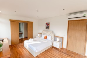 A bedroom with a bed, bedside tables, a wardrobe, and an air conditioning unit. - Stunning Luxury Villas with Expansive Grounds: An Unforgettable Experience (Da Nang)