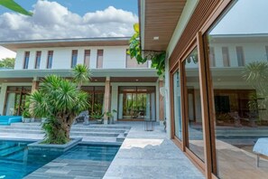 Ein modernes Haus mit Swimmingpool, großen Fenstern und einem gepflegten Garten.