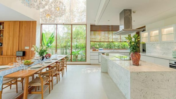 A modern kitchen with a marble countertop, wooden dining table, and large windows. - Stunning Luxury Villas with Expansive Grounds: An Unforgettable Experience (Da Nang)