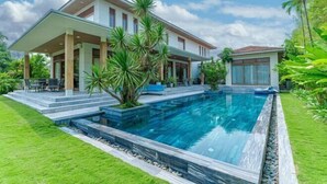 A modern house with a swimming pool, a covered patio, and lush greenery. - Stunning Luxury Villas with Expansive Grounds: An Unforgettable Experience (Da Nang)