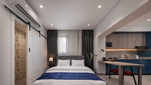 A modern hotel room with a large bed, a dining area, and a kitchenette. - 22 By Spacey (#51) | Studio in Maadi (Cairo)