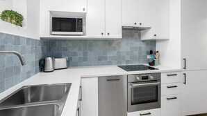 A modern kitchen with white cabinets, a stainless steel sink, a microwave, and a toaster.