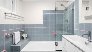 A modern bathroom with a glass shower enclosure, a white bathtub, and a vanity with a mirror.