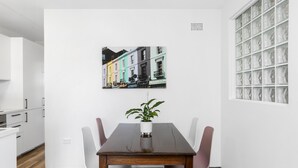 A dining area with a wooden table, white chairs, and a potted plant.