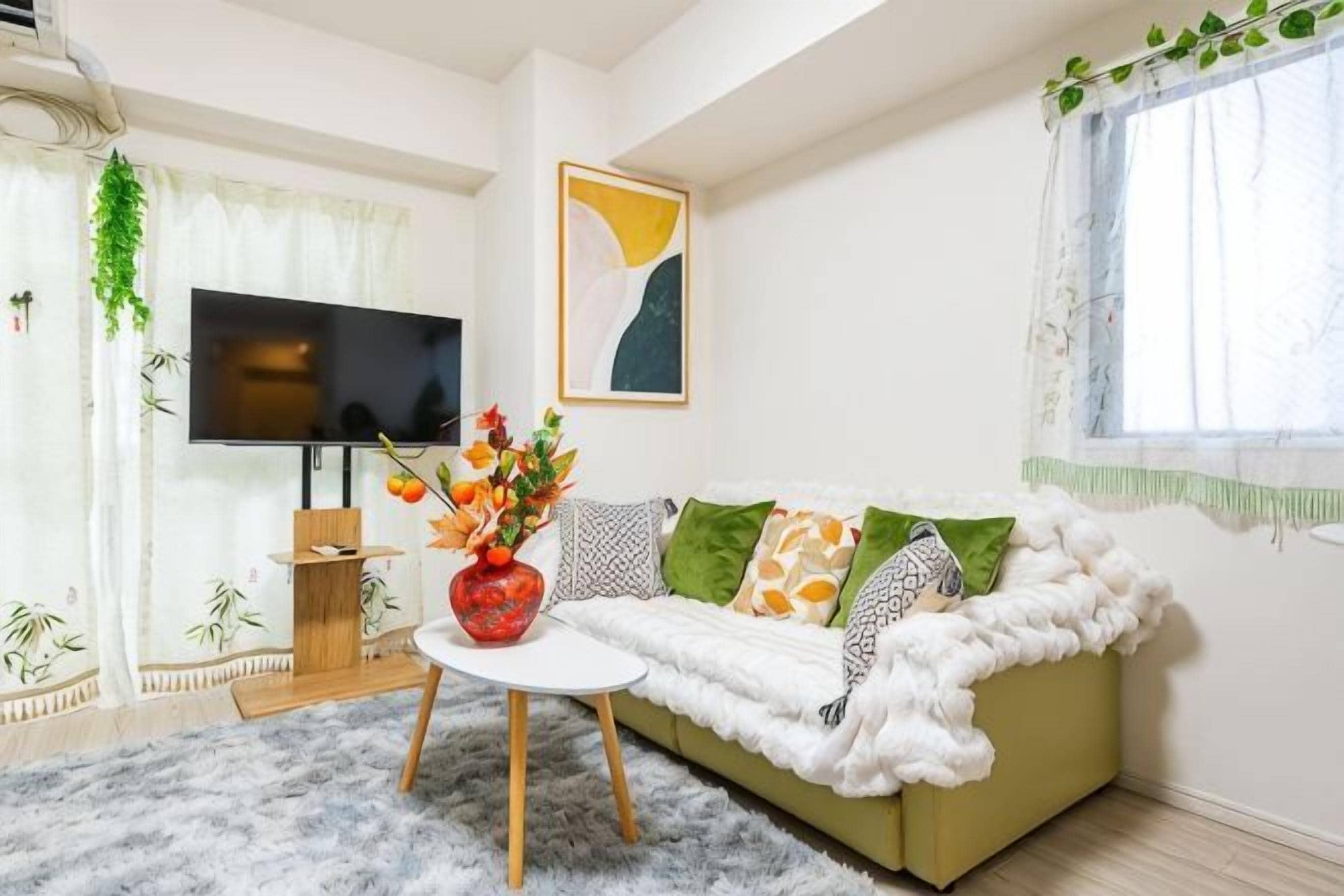 A living room with a sofa, a coffee table, a TV, and a window with curtains.