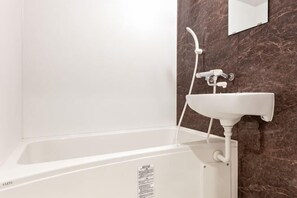 A white bathtub with a shower head and faucet, a white sink, and a marble wall. - Ueno Station 7/2/MAX8/Ginza Asakusa AreaWIFI (Tokyo)