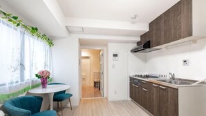 A modern kitchen with wooden cabinets, a white countertop, and a dining area with blue chairs. - Ueno Station 7/2/MAX8/Ginza Asakusa AreaWIFI (Tokyo)