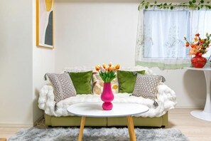 A living room with a sofa, a round coffee table, and a vase with flowers. - Ueno Station 7/2/MAX8/Ginza Asakusa AreaWIFI (Tokyo)