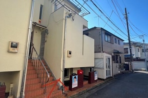 A residential building with a staircase leading to the entrance, a small porch area, and a clear sky. - Ikebukuro No`3 (Tokyo)