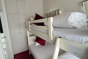 A bunk bed with white bedding and red pillows, a white wardrobe, and a window with curtains. - Ikebukuro No`3 (Tokyo)
