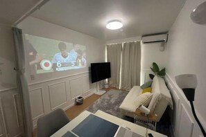 Un salon équipé d’un téléviseur à écran plat, d’un écran de projection, d’un canapé, d’une table basse et d’une plante.