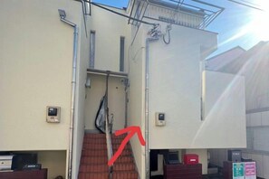 A building with a staircase, a metal staircase railing, and a red arrow pointing to the staircase. - Ikebukuro No`3 (Tokyo)
