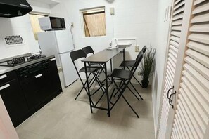 Une cuisine de taille réduite comprenant une table à manger, des chaises, un réfrigérateur et un four à micro-ondes.