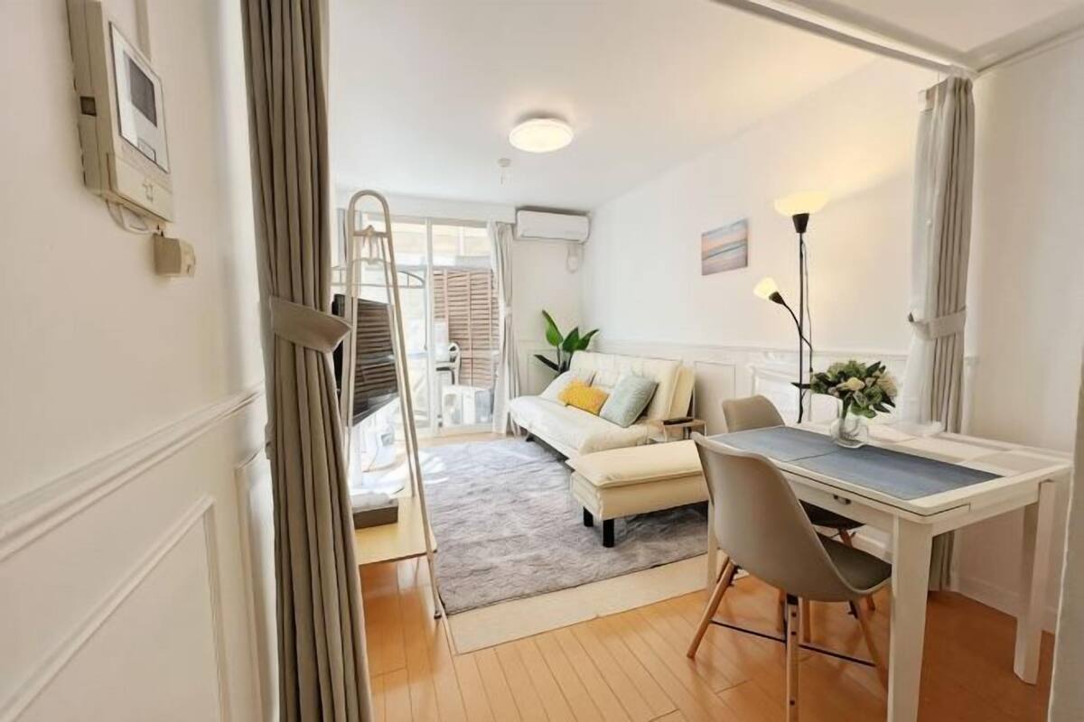 A compact living space with a dining area, a sofa, and a staircase leading to an outdoor area.