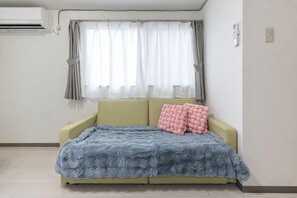 A room with a sofa bed, a window with curtains, and an air conditioning unit. - New/Ueno station 7min walk/Inarimachi station 2min/max 8 people/Ginza Asakusa area (Tokyo)