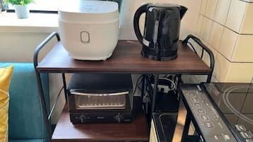 A kitchen with a rice cooker, coffee maker, toaster, and oven.