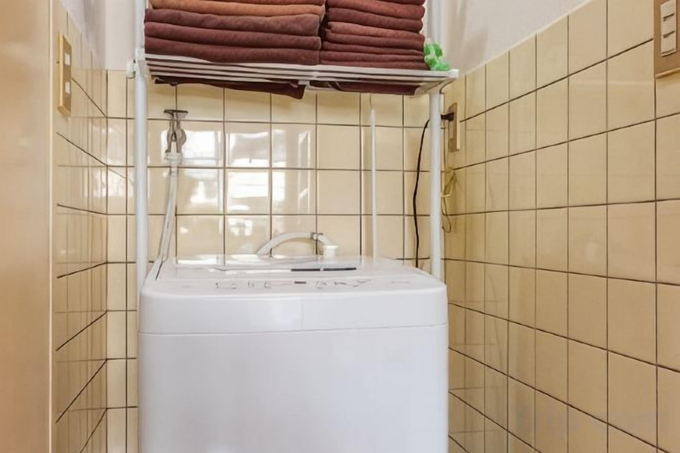 A laundry area with a washing machine and a shelf with folded towels.