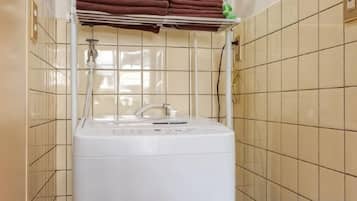 A laundry area with a washing machine and a shelf with folded towels.