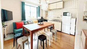 A compact living space with a kitchenette, a dining area, and a seating area with a sofa and chairs. - Guest House SAKURAYA (Tokyo)
