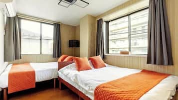 A hotel room with two beds, a flat-screen TV, and large windows with curtains.