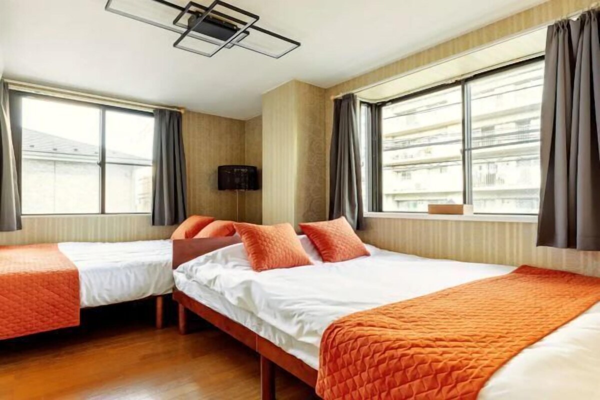 Una camera d'albergo con due letti, una televisione a schermo piatto e ampie finestre.