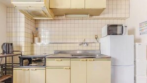A kitchen with white cabinets, a stainless steel sink, a microwave, and a refrigerator. - Guest House SAKURAYA (Tokyo)
