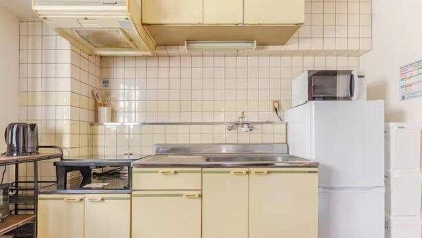 A kitchen with white cabinets, a stainless steel sink, a microwave, and a refrigerator. - Guest House SAKURAYA (Tokyo)