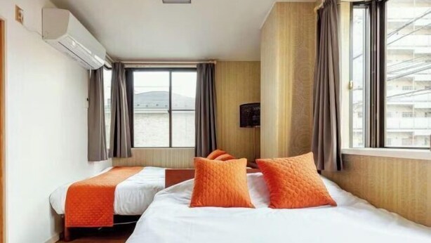 A hotel room with two beds, a large window, an air conditioning unit, and a view of the sea. - Guest House SAKURAYA (Tokyo)