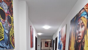 Um corredor com piso de mármore, paredes brancas e obras de arte nas paredes.